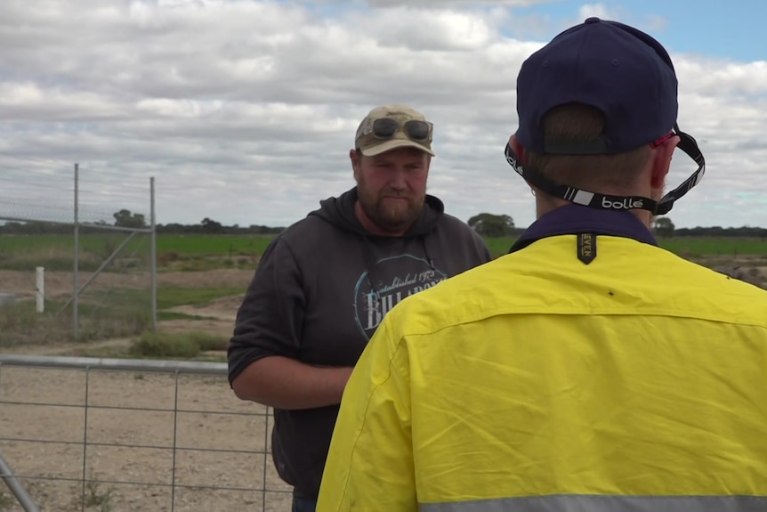 A man talking to a man wearing a yellow high vis shirt