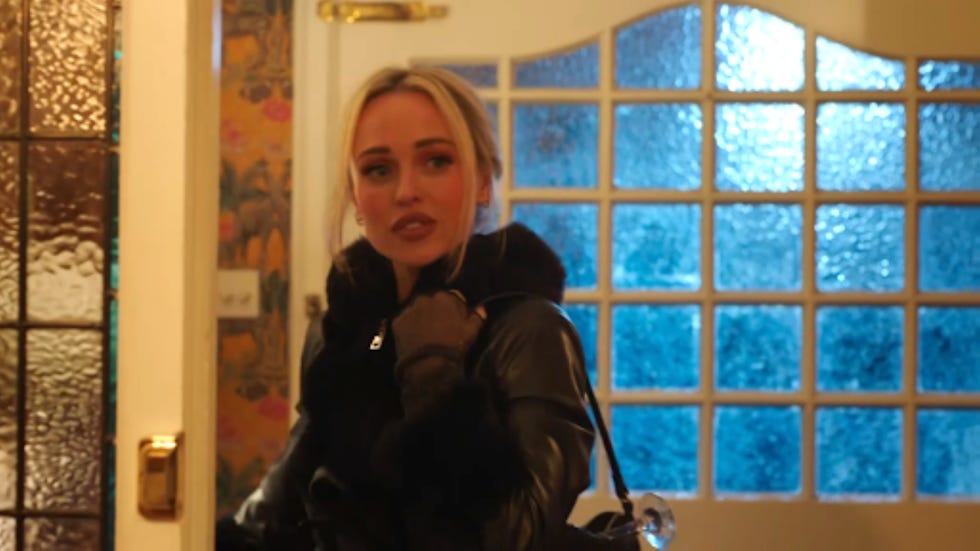 person standing in a foyer with textured glass door and wallpaper