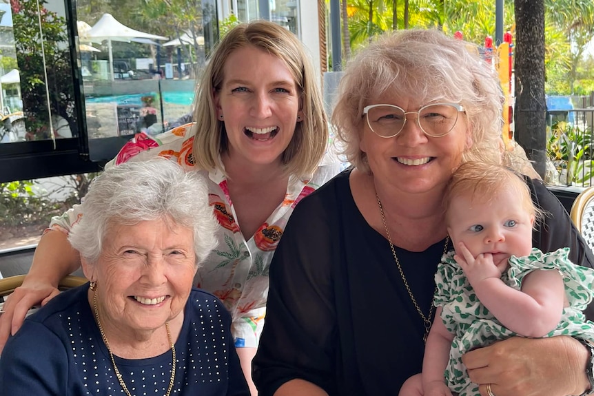 Three women and a baby smiling at the camera.