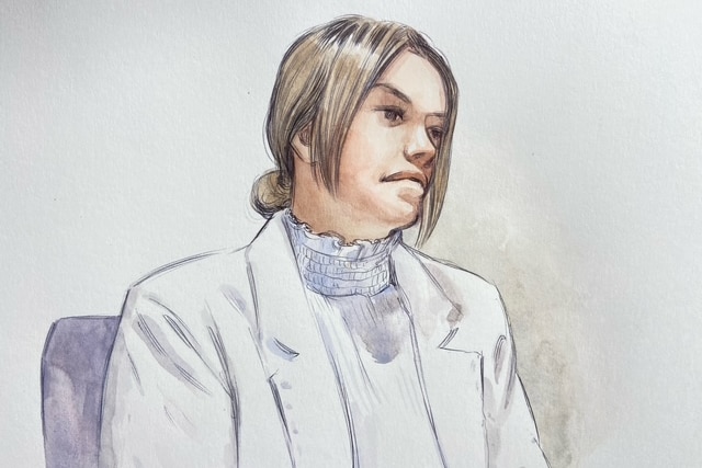 A sketch of a young woman with brown hair tied back, sitting in the dock of a court wearing a white shirt and a white jacket.