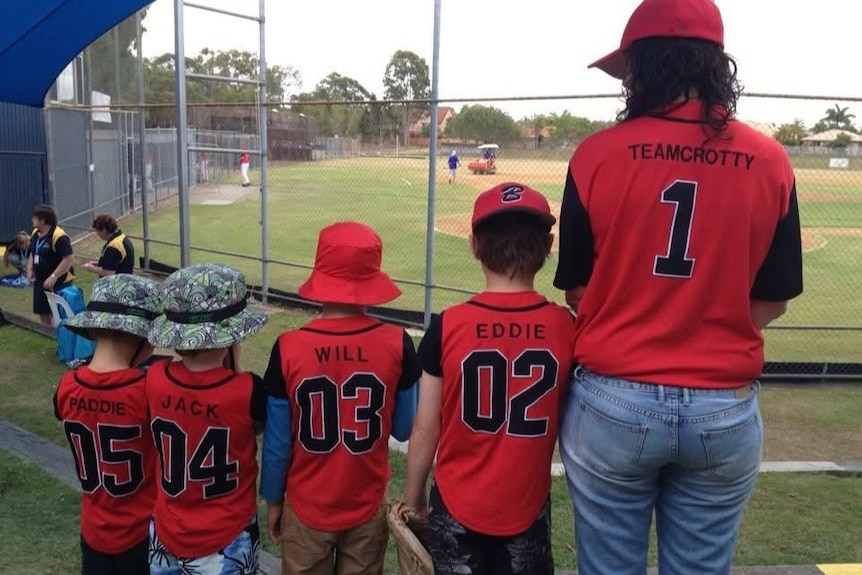 Four young boys and their mother stand with their backs to the camera showing their named jerseys