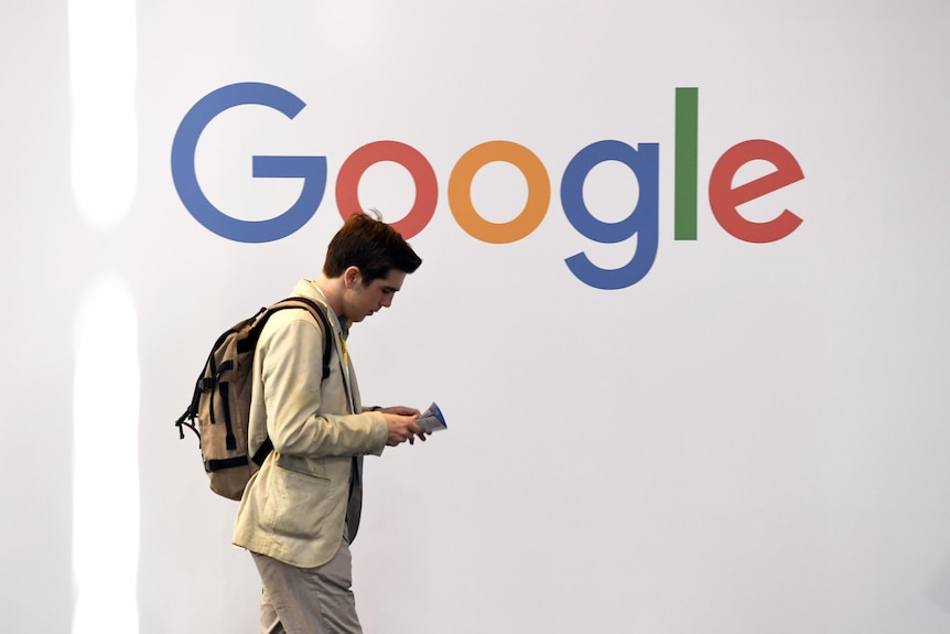 A man walks past a multi-coloured logo spelling Google.