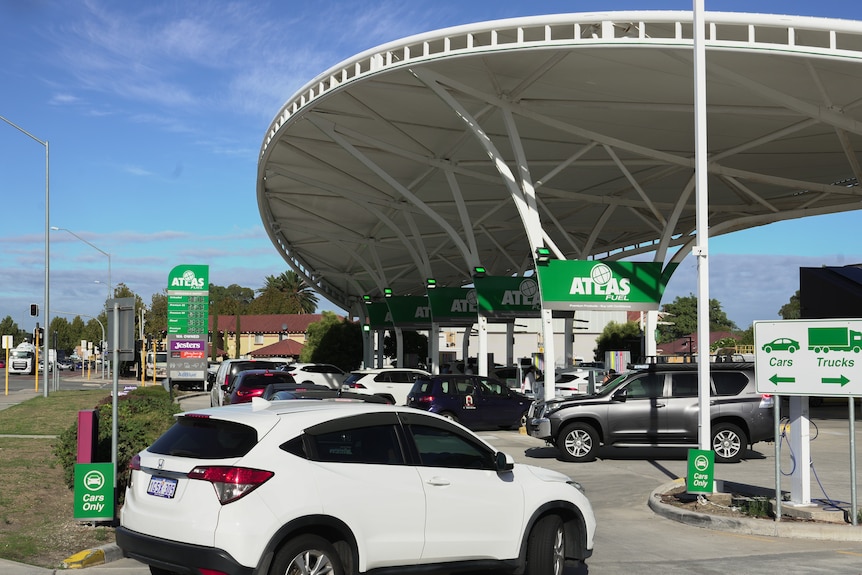 Cars lining up onto a main road for a petrol station.
