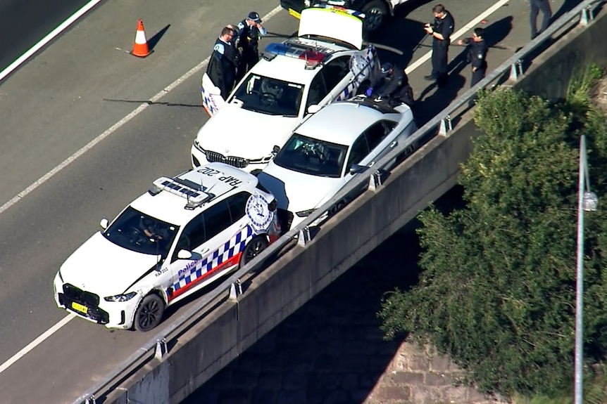 police officers stand next to a car that was rammed by police after a police chase