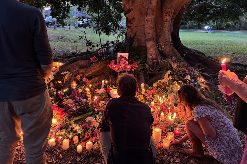 A group of people knell in front of candles