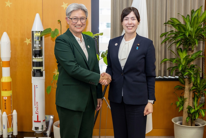 Two women smile while shaking hands
