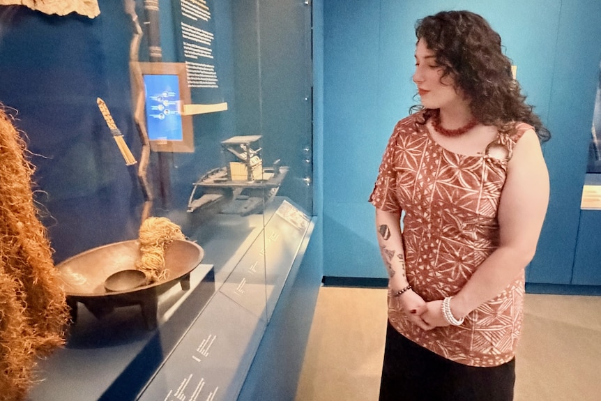 A young woman looks into a glass cabinet of historical objects.