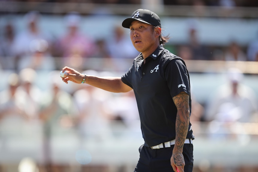 Golf thanking fans for applause, raising his arm with the golf ball in hand