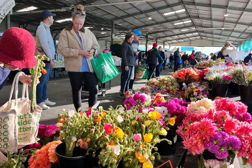 People stand and look at bunches of flowers.