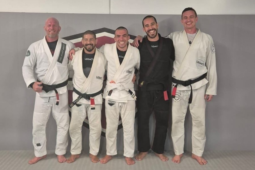 Group of men in line wearing martial arts robes.