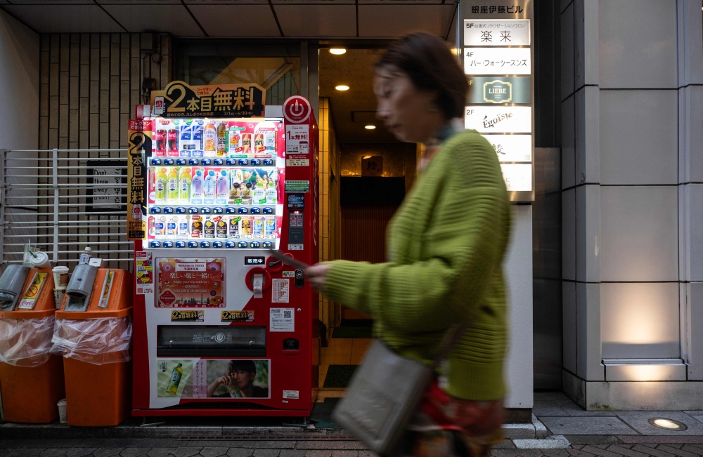 A woman walks past a vending machine on a side street in Tokyo’s Ginza district April 7, 2026. — AFP pic