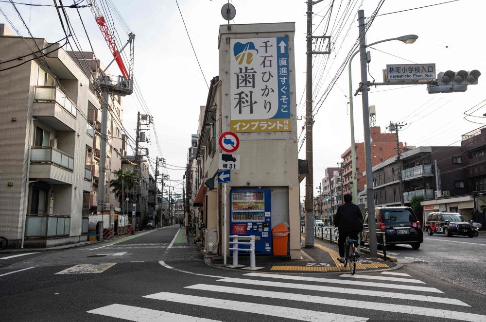 A man cycles past a vending machine setup at an intersection in Tokyo’s Bunkyo district on April 14, 2026. — AFP pic