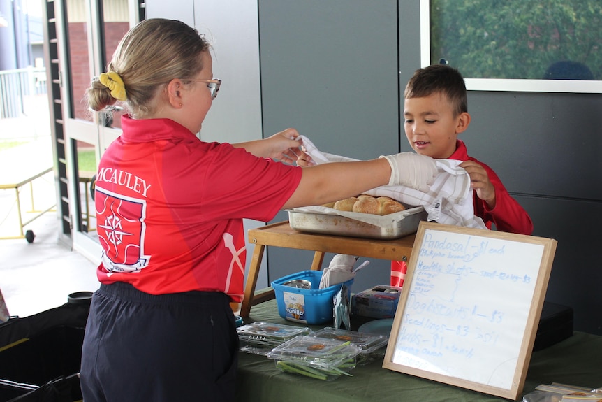 Two children prepare food at a farmers' market