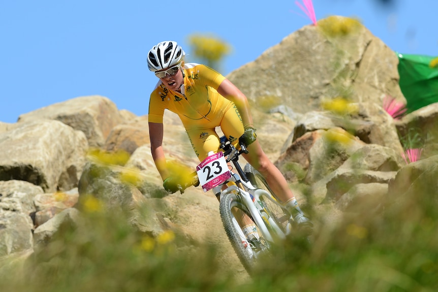 Rebecca Henderson rides through rocks in yellow kit
