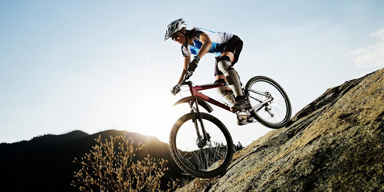 mountain biker ascending a rocky slope under a clear sky