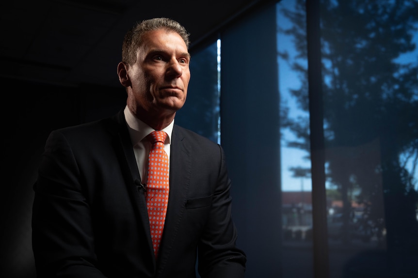 side profile of Cory Bernardi in a business suit in a dark room next to a large window