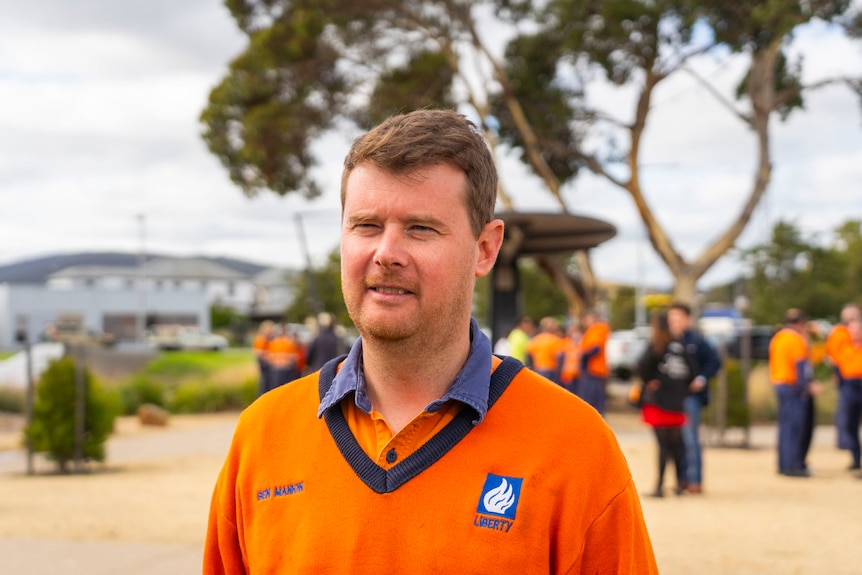 A man wearing a bright orange shirt standing outside