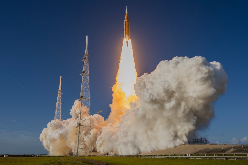 A rocket blasts off in a cloud of smoke and fire.