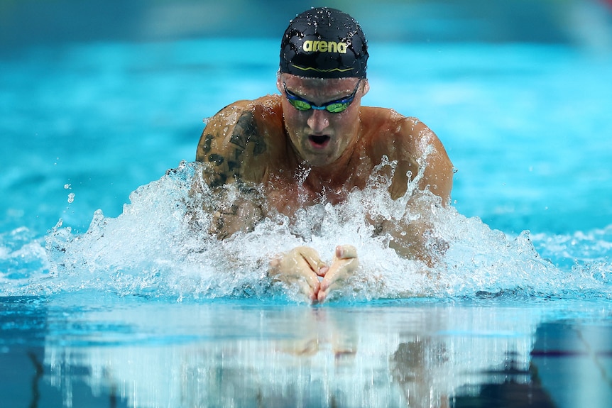 Sam Williamson wearing goggles and a cap, swimming breaststroke in a pool.