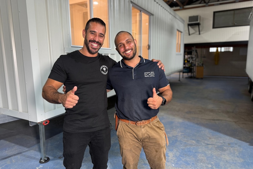 Two men smiling, giving thumbs up.