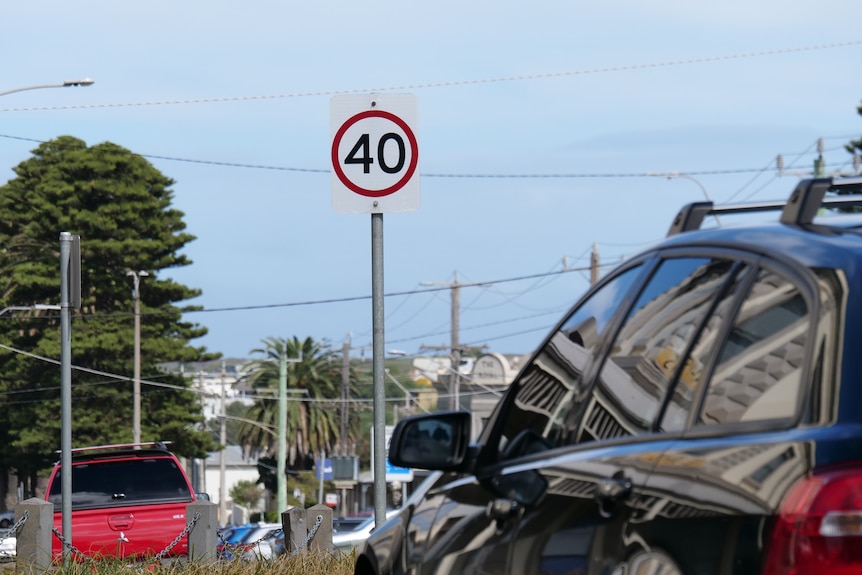 A car and a 40-kilometre-an-hour speed limit sign.