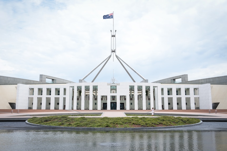 A wide, white building with an Australian flag held above it.