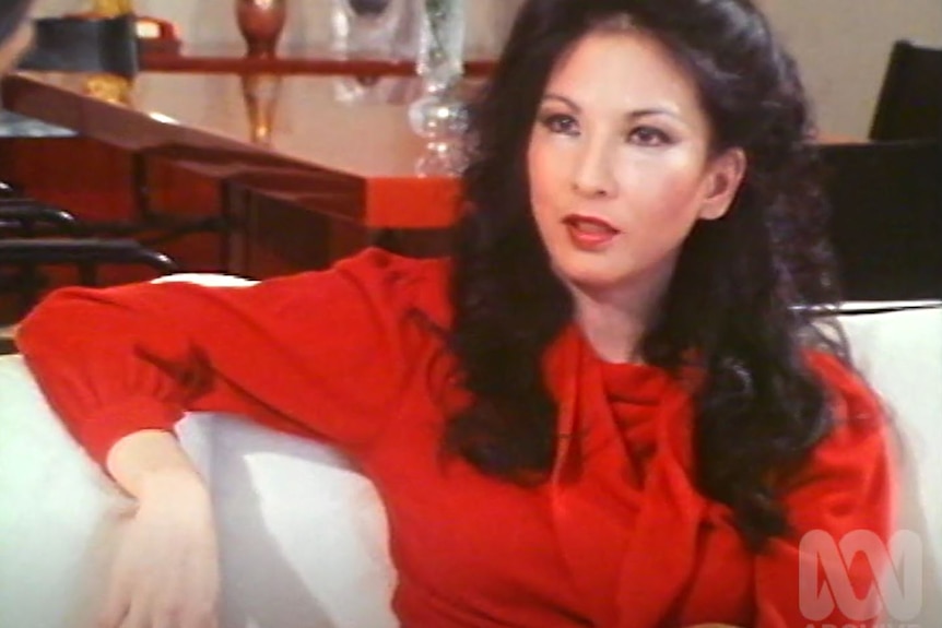 A screenshot from a grainy VHS video shows Rose Hancock Porteous in a bright red silk shirt.