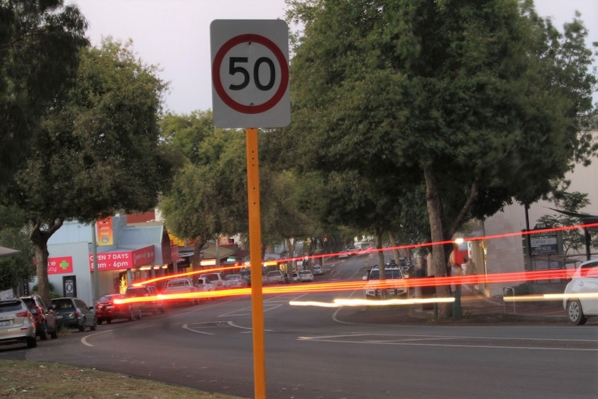 A speed sign, on country street, with a flash of light.