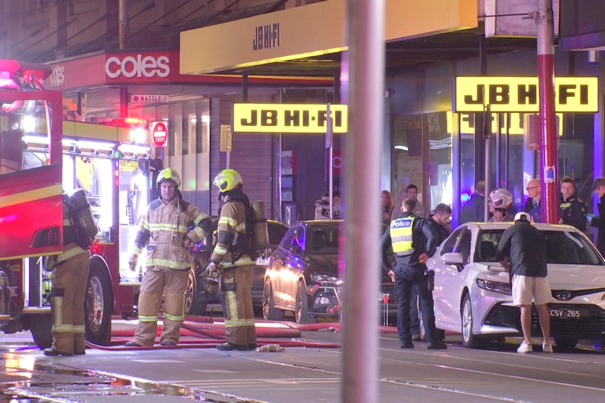Firefighters stand on the street.
