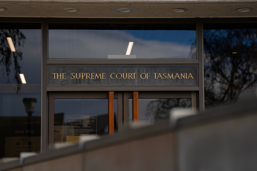A sign at the front of a glass and brick building which reads 'Supreme Court'.