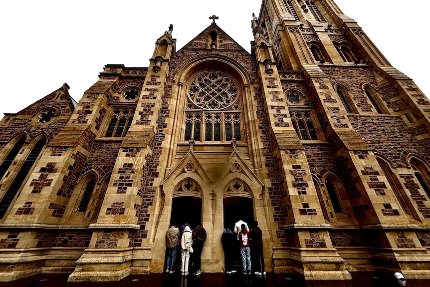 Several people stand at the two-door entrance of a grand cathedral looking inside