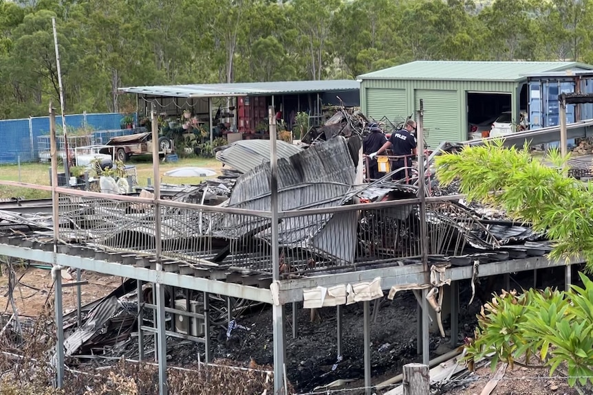 Police investigators among charred remains of a house