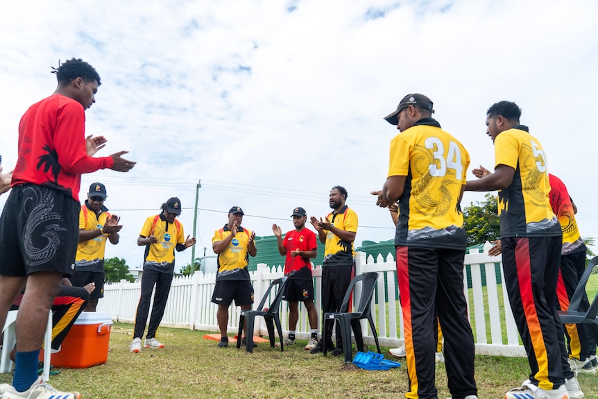 A group of cricketers in a circle doing a warm-up drill. 