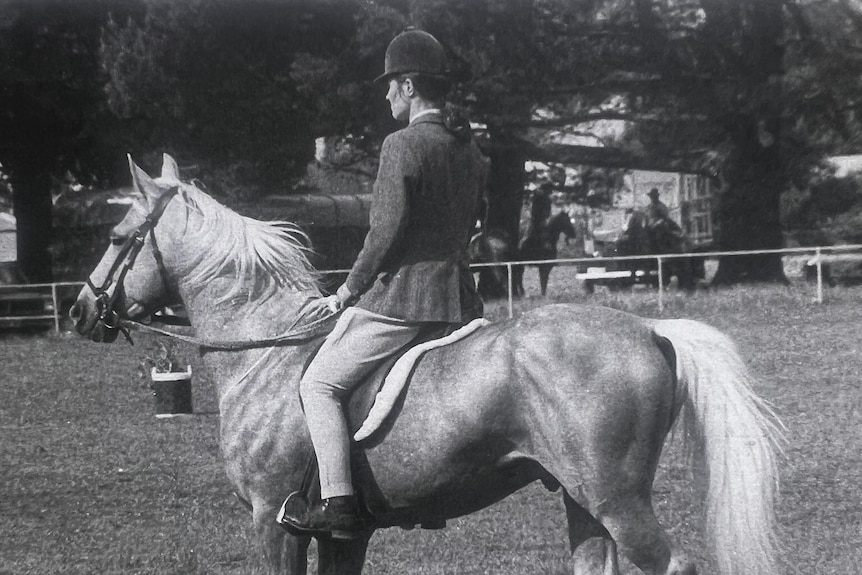 A black-and-white image of a young woman on a palomino horse.