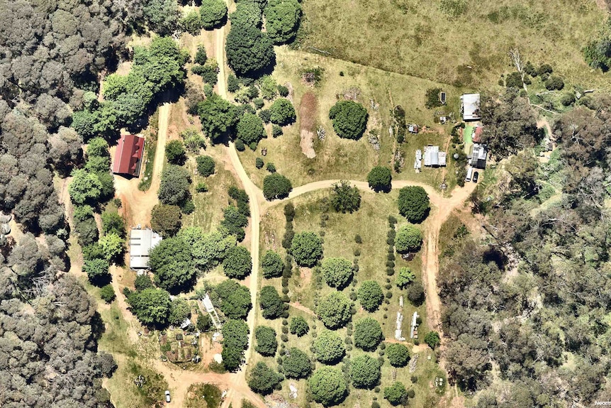 An aerial view showing a red house amongst greenery.