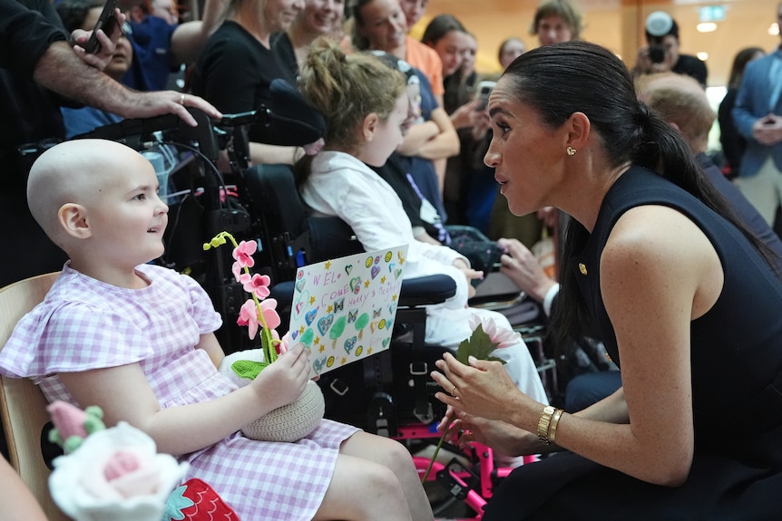 A young girl gives a flower to Meghan