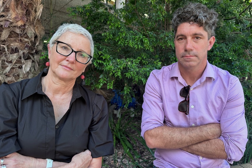 Two people sitting outside with their arms folded