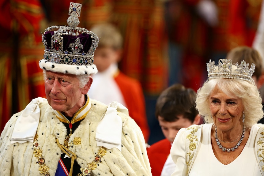 A man wearing a red crown standing next to a woman wearing a silver crown.