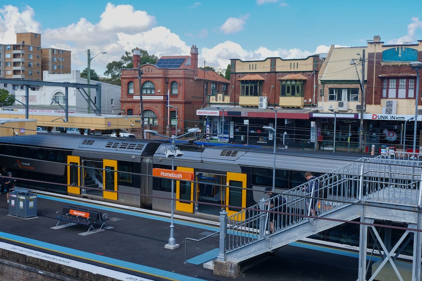 a train stopped at a train station while commuters move around the platform