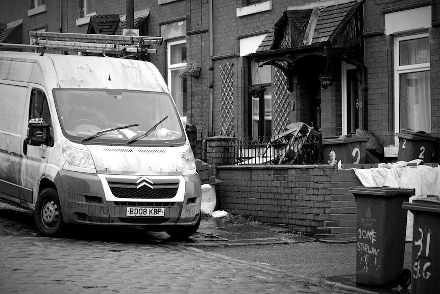 Run-down homes and a dirty white van.