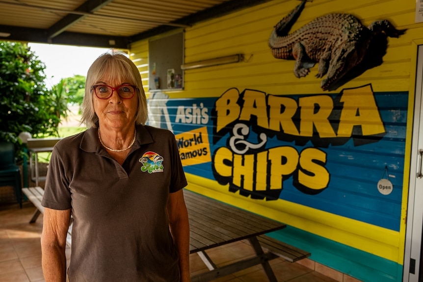 Woman standing in front of fish and chip shop.