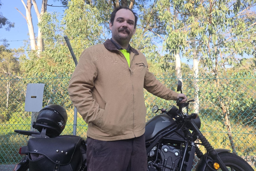 A man standing in front of a motorbike.