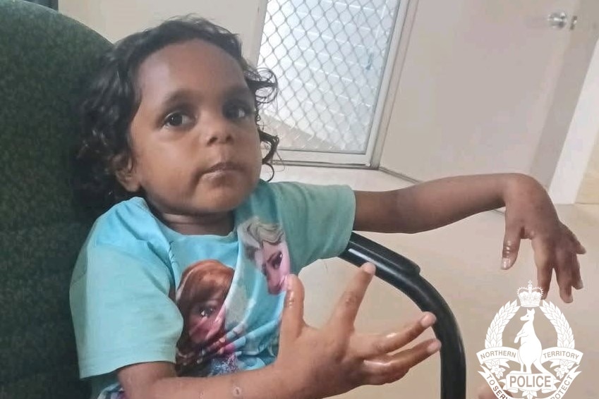 young girl in blue shirt sits in chair holding arms out front