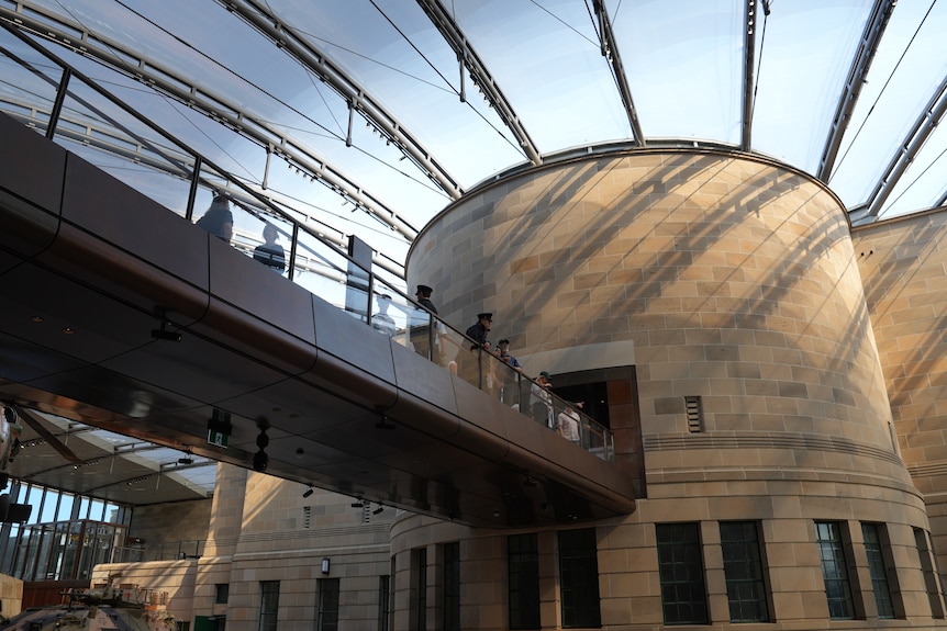 A view of stone walling and a glass ceiling near a footbridge.