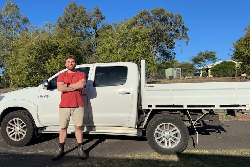 A man stands in front of a white toyota hilux.
