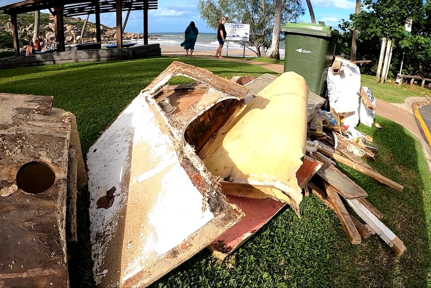 A pile of rubbish and wood left next to a council bin