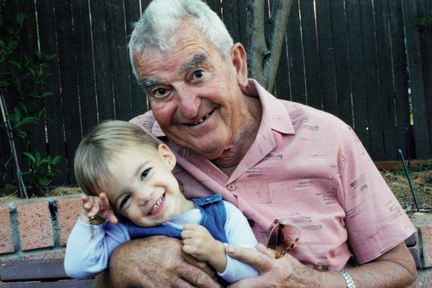 An old man holds his great granddaughter affectionately.