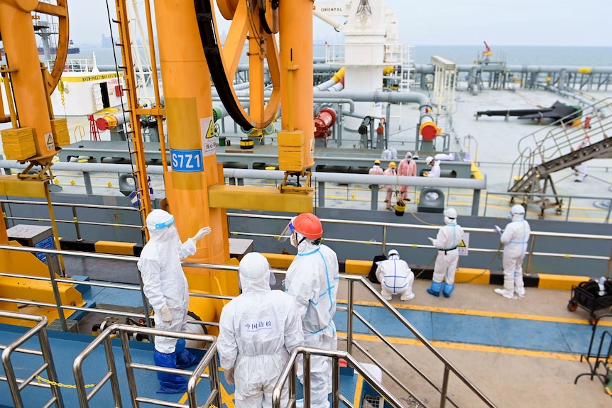 Inspection officers in protective suits on a tanker.