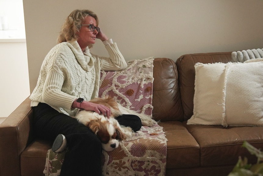 A woman sitting on a couch with a dog.
