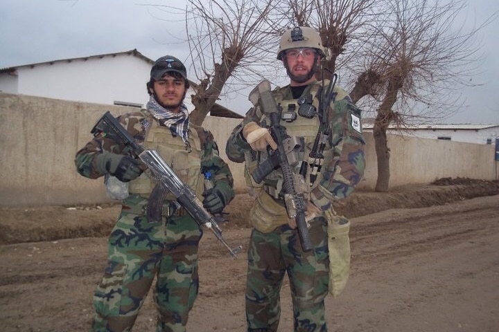 Two men wearing camoflague unifroms and holding rifles.